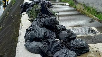 sacos de lixo amontados ao lado de canal #paratodosverem