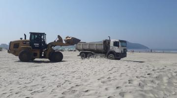 retroescavadeira leva areia para outro caminhão na praia #paratodosverem