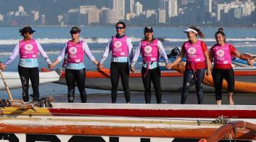 mulheres com colete ao lado de canoa na praia #paratodosverem