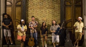 pessoas encostadas em uma parede, algumas com instrumentos musicais #paratodosverem