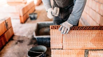 mãos mexendo em tijolos em obra #paratodosverem