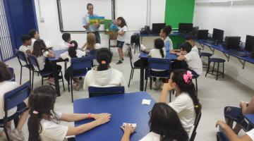 pai de aluno lê livro e crianças observam em sala de aula #paratodosverem