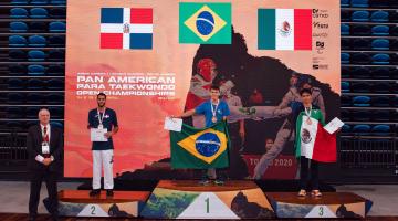 atletas no pódio com medalhas e segurando bandeira #paratodosverem