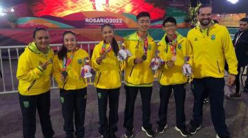atletas com casaco amarelo mostram medalhas #paratodosverem