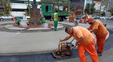 trabalhadores usando máquina para cimentar piso junto a uma praça #paratodosverem