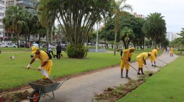 trabalhos realizam serviço na grama do jardim da orla #paratodosverem