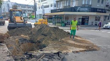 via com grande buraco e terra, trator e funcionário #paratodosverem