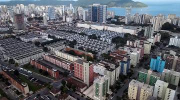 vista aérea de bairro com muitos prédios e o mar ao fundo. #paratodosverem 