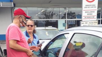 educadora orienta idoso ao lado do veículo #paratodosverem