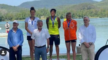 atletas no pódio com medalhas e rio ao fundo #paratodosverem