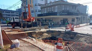 obra na via com buraco grande e caminhão ao lado levantando uma cobertura #paratodosverem