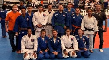 judocas com quimono posam para foto no tatame #paratodosverem