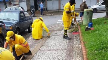 trabalhadores realizam serviços de raspação agachados no meio fio e ao lado de jardim #paratodosverem