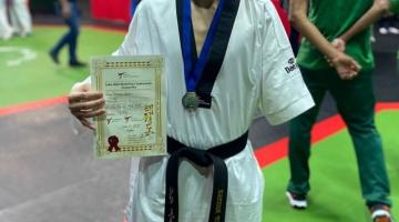 atleta de quimono exibe diploma e medalha #paratodosverem