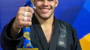 atleta de quimono exibe medalha de ouro #paratodosverem