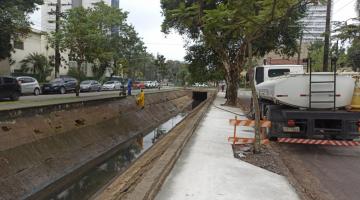 homem trabalhando no canal e calçada com concreto e caminhão ao lado #paratodosverem