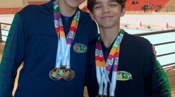 irmãos abraçados com medalhas em ginásio #paratodosverem