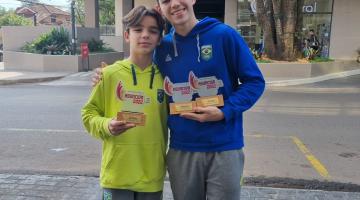 irmãos abraçados em rua exibem troféu #paratodosverem
