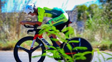 atleta em cima de bike em pista cerca de vegetação #paratodosverem