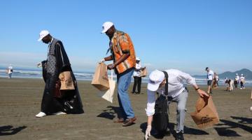 participantes da conferencia recolhem lixo na praia #paratodosverem