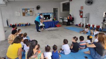 crianças sentadas acompanham teatro de fantoche #paratodosverem
