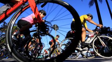 imagem de ciclistas pedalando com roda de bicicleta em primeiro plano #paratodosverem