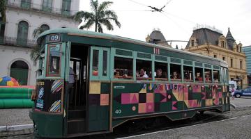 bonde com pessoas dentro circula por rua no centro histórico #paratodosverem