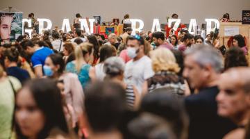 várias pessoas se movimentando dentro de um salão. Ao fundo se lê gran bazar. #paratodosverem