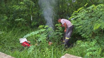 homem está no meio do mato próximo a um material que queima com fumaça. #paratodosverem 