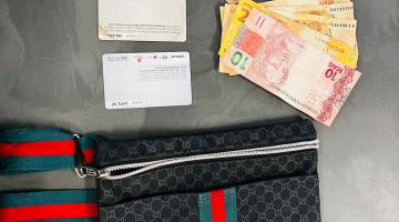 carteira, dinheiro, cartões, relógio e celular dispostos sobre uma mesa. #paratodosverem 