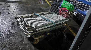 carrinho de supermercado com grelhas de ferro. A viatura da guarda municipal está atrás. #paratodosverem 