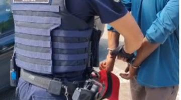 guarda civil municipal está em pé algemando homem que está de costas. #paratodosverem 