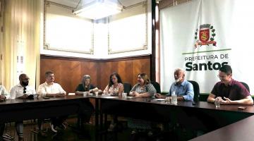pessoas conversam reunidas em torno de mesa. #paratodosverem