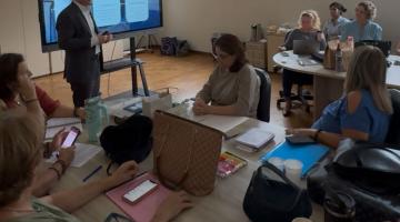 palestrante fala aos educadores na frente de tela #paratodosverem 