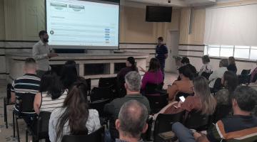 servidores reunidos em salão assistem palestra com telão. #paratodosverem