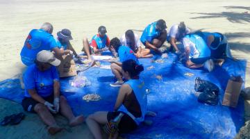 pessoas colhendo lixo na praia #paratodosverem