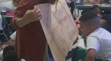 professora mostra mapa a aluno #paratodosverem
