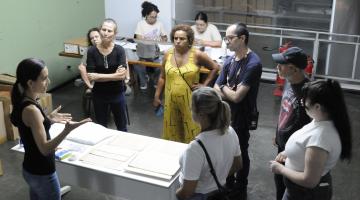 pessoas em volta de uma mesa observam documentos. #paratodosverem