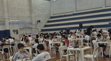 crianças sentadas jogando xadrez em mesas #paratodosverem 