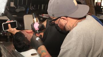 tatuador cria imagem em um homem que está deitado. #paratodosverem