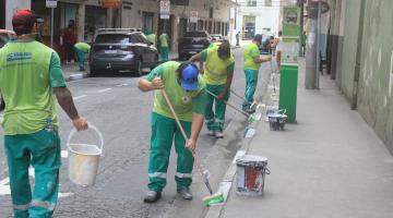 Homens realizam pintura das guias na calçada #paratodosverem