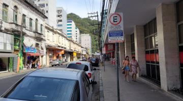 rua do centro com veículos estacionados à direita e placa referente à zona azul. #paratodosverem
