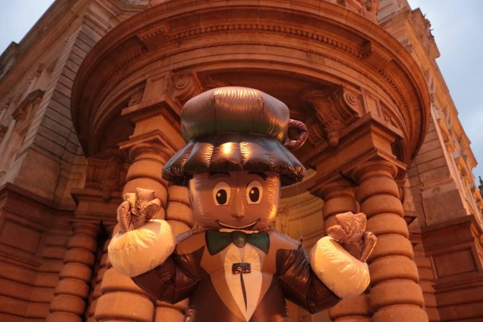 o mascote do festival, um boneco gigante, na frente do Museu do Café.#paratodosverem