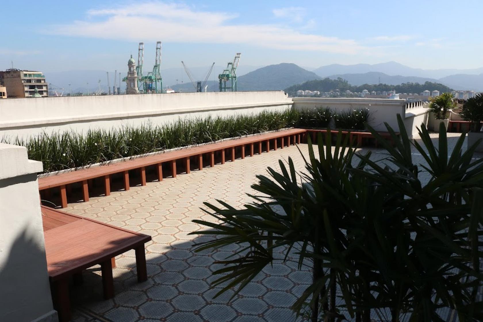 vista geral de área ao ar livre no 5º e último andar do paço paço, com bancos de madeira e plantas. #paratodosverem