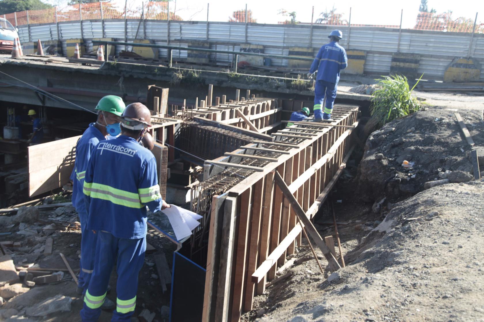 três operários estão ao lado de estrutura da obra #paratodosverem 