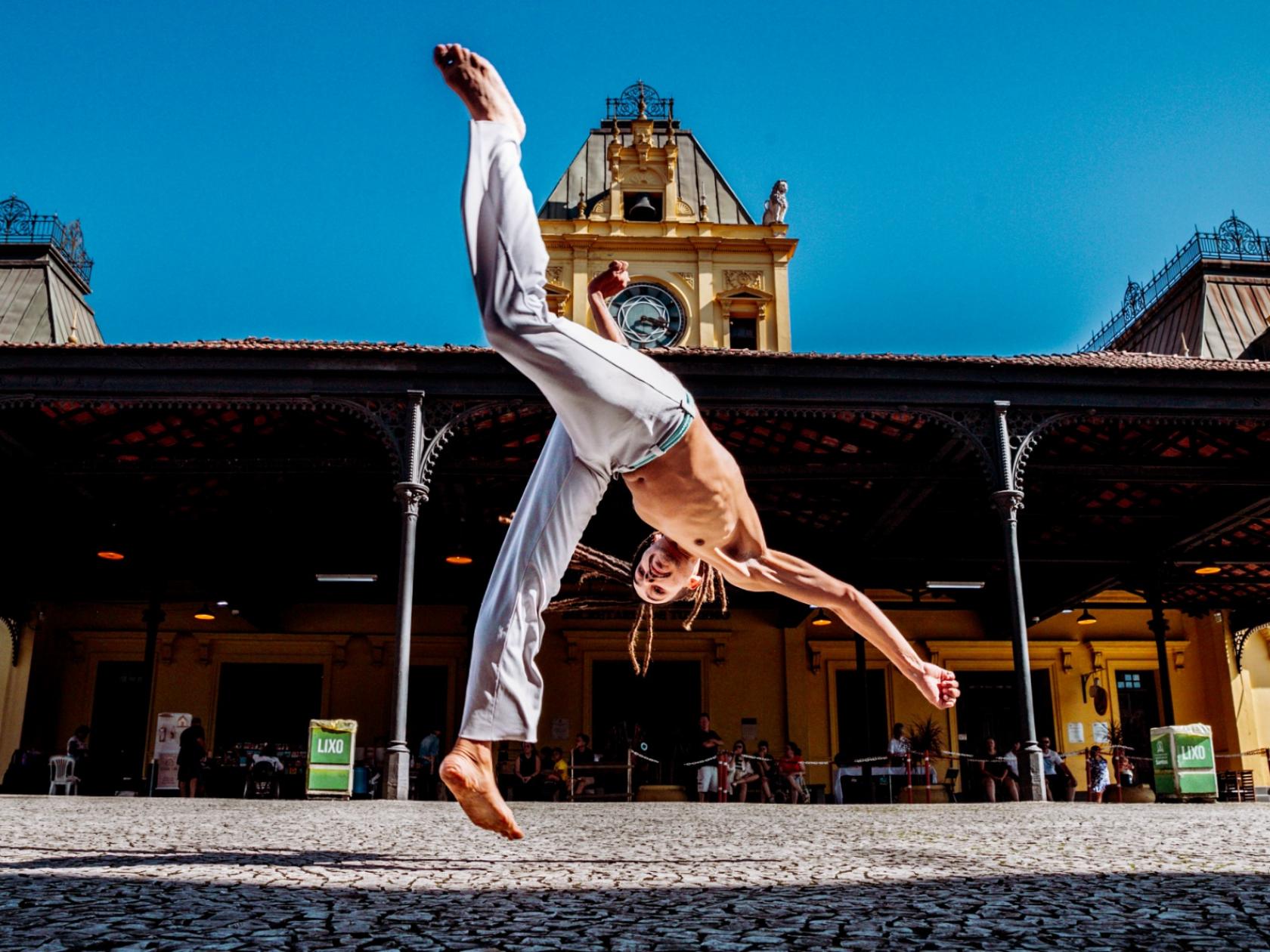 homem faz movimento de capoeira na frente da estação do valongo #paratodosverem 