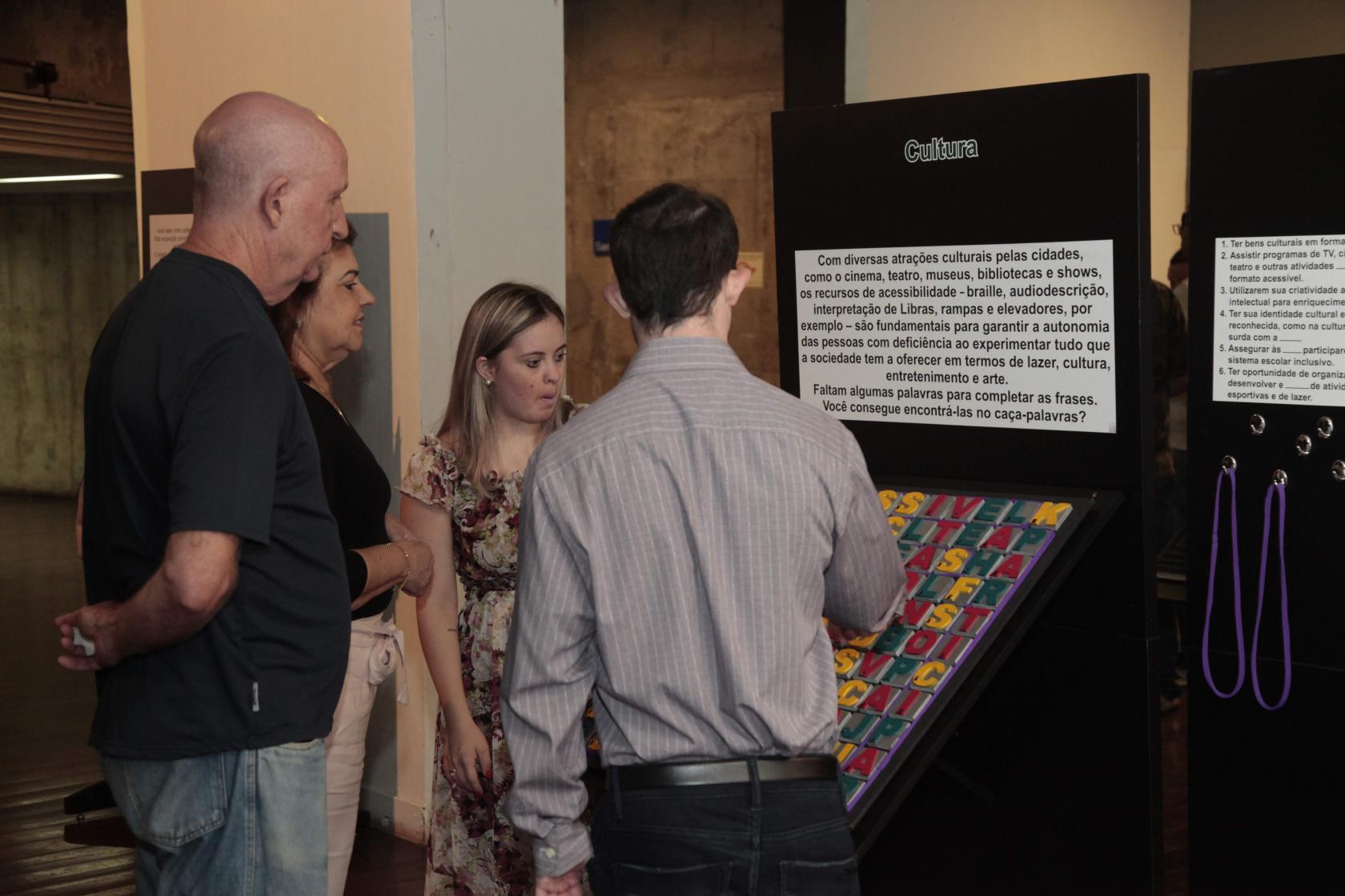 pessoas olhando peças da exposição #pracegover