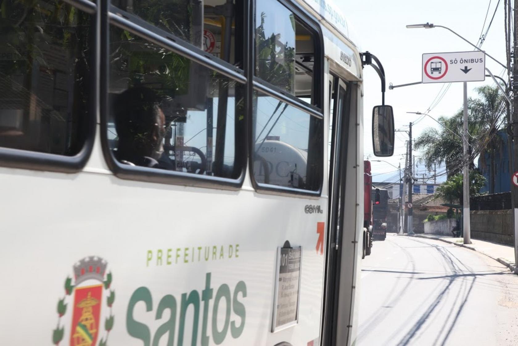 ônibus passa em faixa com placa em cima #paratodosverem 