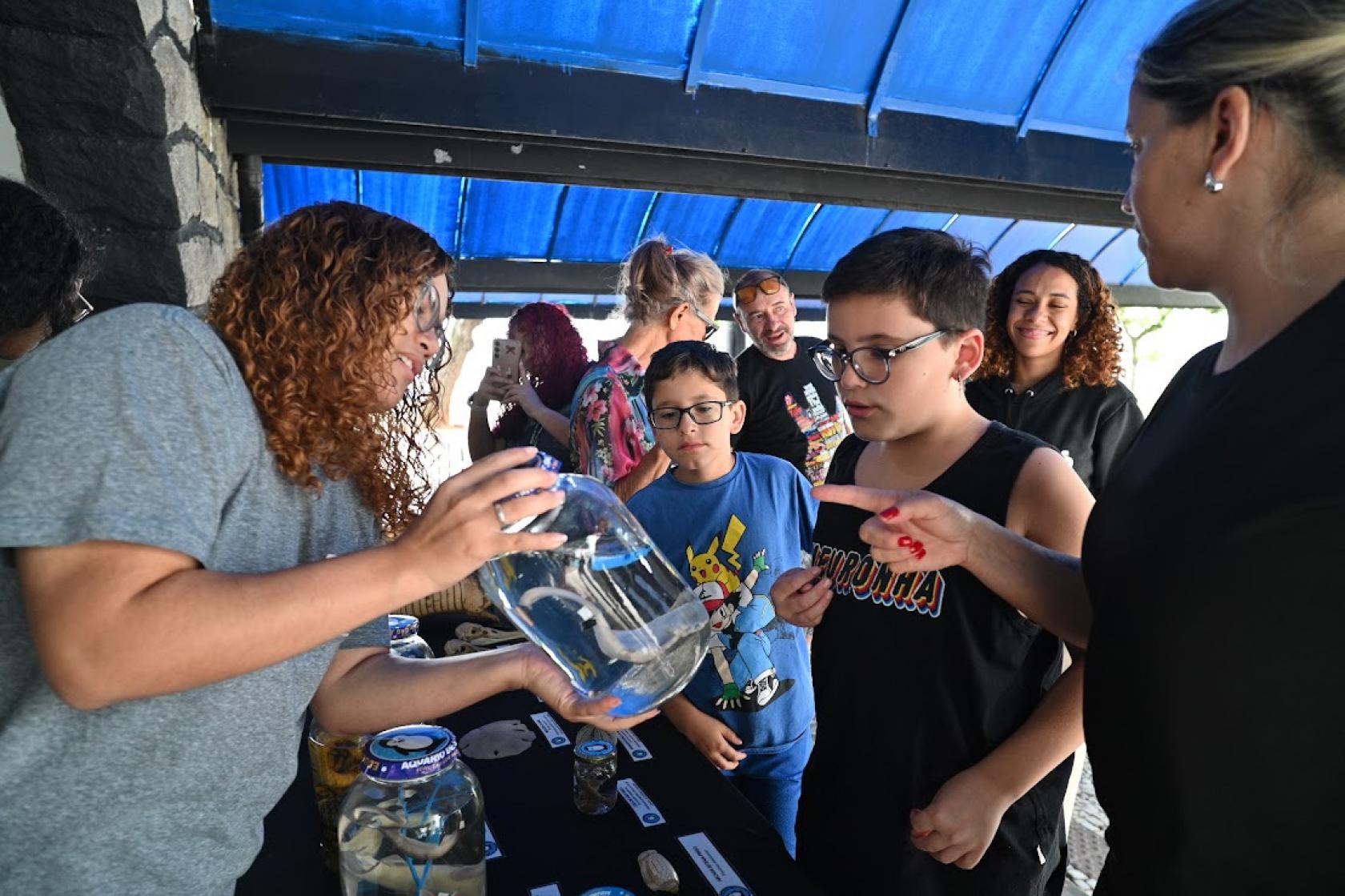 monitora mostra vidro com animal para aluno #paratodosverem 