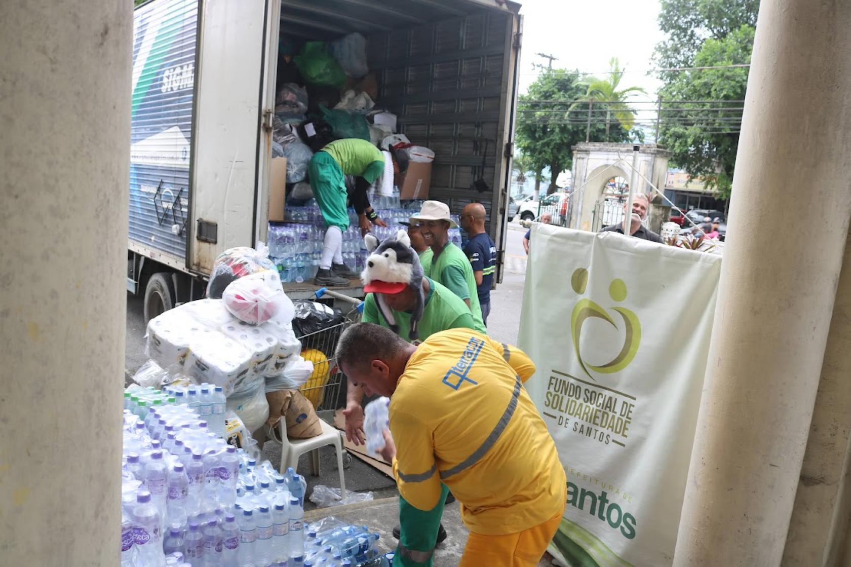 trabalhadores colocam doações em caminhão #paratodosverem 